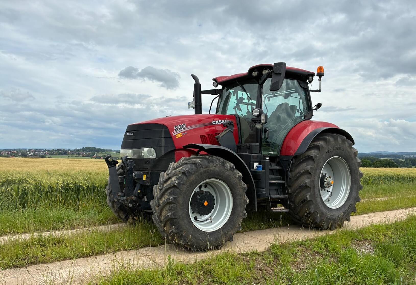 Roter Traktor der Marke Case IH steht auf einem Feldweg neben einem Getreidefeld – Einsatzgebiet der Reifendruckregelanlage VariQtire